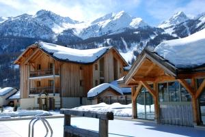 a ski lodge with snow covered mountains in the background at Chalet Apartment Monêtier in Le Monêtier-les-Bains