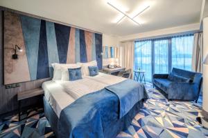 sypialnia z dużym łóżkiem i niebieskim krzesłem w obiekcie Wellton Riverside SPA Hotel w Rydze