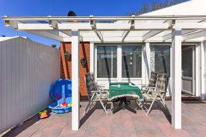 a pergola with chairs and a table on a patio at Ferienhaus Brigitte in Bensersiel