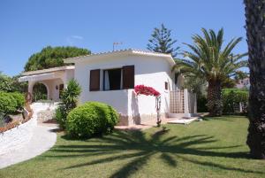 una casa blanca con palmeras y un patio en Villa Isabel, en Son Bou