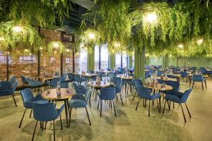 uma sala de jantar com mesas, cadeiras e plantas em Wellton Riverside SPA Hotel em Riga