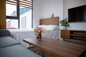 una sala de estar con una mesa con flores. en Alaya 10 Apartment en Hanói