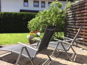 two lawn chairs sitting on a patio with flowers at Appartement Hildegard in Rieden am Forggensee