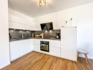 a white kitchen with white cabinets and a wooden floor at Meerestraum in Grömitz