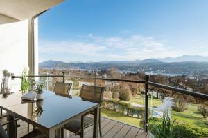 a balcony with a table and chairs and a view at Haus Aussicht - Ferienwohnungen Velden in Velden am Wörthersee