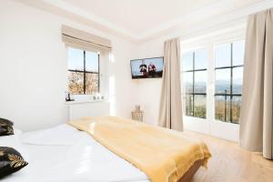 a white bedroom with a bed and windows at Haus Aussicht - Ferienwohnungen Velden in Velden am Wörthersee +102 photos