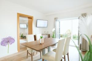 ein Esszimmer mit einem Holztisch und weißen Stühlen in der Unterkunft Haus Aussicht - Ferienwohnungen Velden in Velden am Wörthersee