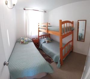 a room with two bunk beds and a mirror at Cerquita del Mar Departamento Entero in La Serena