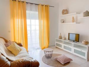 a living room with a couch and a television at Apartamento T2 Carvoeiro-Lagoa preços acessíveis in Lagoa