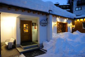 une maison avec de la neige sur son côté dans l'établissement Sport Hotel Alpina, à Madesimo