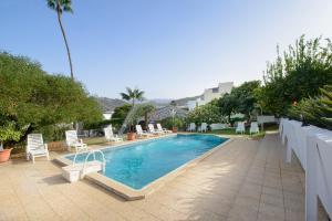 einen Pool mit weißen Stühlen und einem Pool in der Unterkunft Las Esterlicias ( Villa Rural Ecológica ) in Teror