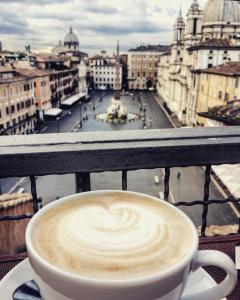 eine Tasse Kaffee auf einem Balkon mit Stadtblick in der Unterkunft Navona 49 Luxury Suites&Apartment in Rom