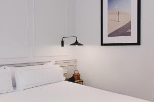 ein weißes Bett mit weißen Kissen und einer schwarzen Lampe in der Unterkunft Helen Berger Boutique Hotel in Valencia