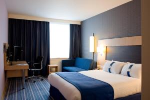 a hotel room with a large bed and a blue chair at Holiday Inn Express Rotherham - North, an IHG hotel in Rotherham