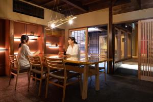 two women sitting at a table in a restaurant at 民家ホテル「金ノ三寸」(かねのさんずん） in Takaoka