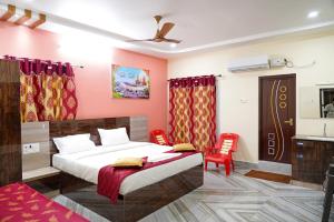 a bedroom with a bed and two red chairs at Devansh Bhanu Residency DBR in Srikalahasti