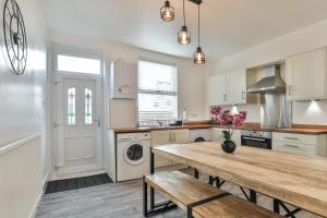 a kitchen with white cabinets and a wooden table at Hidden Gem-Open To Book-Super Location in Sheffield