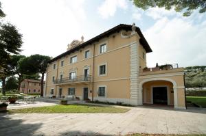 un grand bâtiment jaune avec un balcon au-dessus dans l'établissement Isola Polvese Resort, à Castiglione del Lago