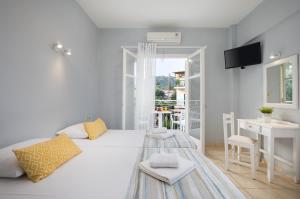 a white bedroom with a white bed and a desk at Bella Vista Beach Hotel in Benitses