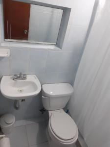 a white bathroom with a toilet and a sink at Thelmar Rooms Cancun in Cancún