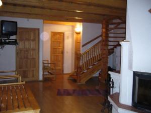 a living room with a wooden staircase and a tv at Chata Ala in Demanovska Dolina