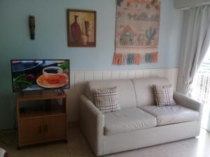 a living room with a white couch and a tv at DESCANSO IDEAL II CABO CORRIENTES in Mar del Plata