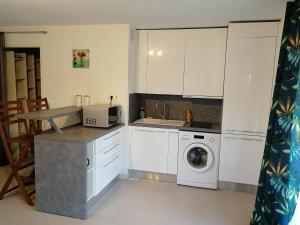 a kitchen with white cabinets and a washing machine at Lovely Studio & Garden - près des plages Cagnes-sur-Mer in Cagnes-sur-Mer