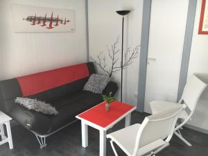 a living room with a black couch and white chairs at Chalet orange naturiste la Jenny in Le Porge