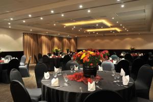 Safari Hotel & Convention Centre في روستنبرج: غرفة مأدبة مع طاولات وكراسي مع الزهور