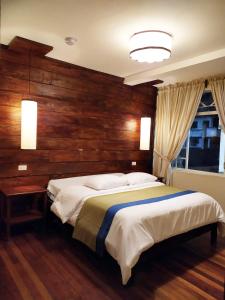 a bedroom with a large bed with a wooden wall at Los Ríos de Baños in Baños