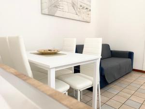 mesa de comedor blanca con sillas blancas y sofá en Il Viaggiatore Serapo, en Gaeta
