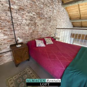 1 dormitorio con cama morada y pared de ladrillo en El Almacen Rentals en Mar del Plata