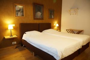 a bedroom with a large white bed with two lamps at Focus Hotel in Kortrijk