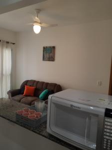 a living room with a couch and a microwave at Apartamentos Gratitude in Ubatuba