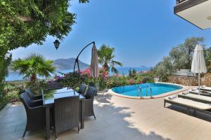 a patio with a table and chairs and a swimming pool at Stunning Seaviews in Kalkan