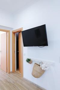 una TV a schermo piatto appesa a un muro bianco di Casas de Mar - Casa Estrela do Mar a Olhão