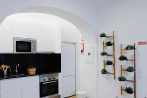 una cucina con armadi bianchi e piante in vaso sul muro di Casas de Mar - Casa Estrela do Mar a Olhão