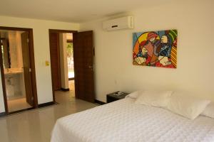 1 dormitorio con 1 cama y una pintura en la pared en Sun Bay Pipa Hotéis, en Pipa