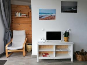 a white desk with a television and a chair at casal do melro in Ericeira