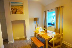 a dining room with a wooden table and a window at Staycation at Pine Cottage, a newly refurbished holiday cottage in Goodwick