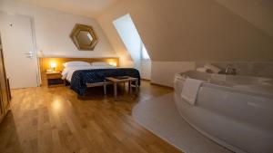 a bedroom with a bed and a bathtub and a bath tub at Hôtel du Cheval Blanc - City center in Bulle