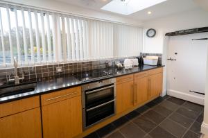 a kitchen with wooden cabinets and a sink and a window at Anns Cottage, Chapel Stile in Chapel Stile