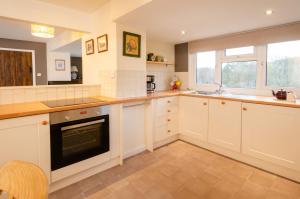 a large kitchen with white cabinets and a sink at Langdale Hideaway in Chapel Stile