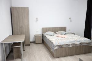 1 dormitorio con cama, escritorio y mesa en Hățașul Bunicului, en Arefu