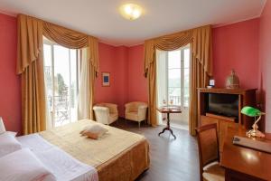 Schlafzimmer mit roten Wänden, 2 Betten und einem TV in der Unterkunft Excelsior Palace Hotel in Taormina