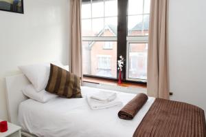 1 dormitorio con cama blanca y ventana en Campbells Guest House, en Leicester