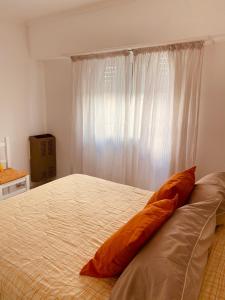 Los Robles Centro في تانديل: وسادة برتقالية على سرير في غرفة النوم