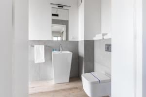 a white bathroom with a toilet and a sink at Stan Apartamenty Yacht Park Gdynia in Gdynia