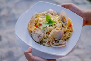 a person holding a plate of pasta with seafood at La Playa Estrella Beach Resort in Bantayan Island