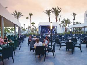 a rendering of a restaurant with people sitting at tables at Hotel Riu Palace Meloneras in Maspalomas